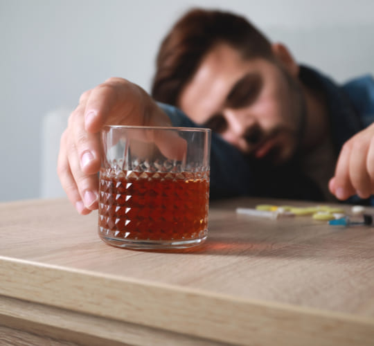 мужчина со стаканом алкоголя спит за столом